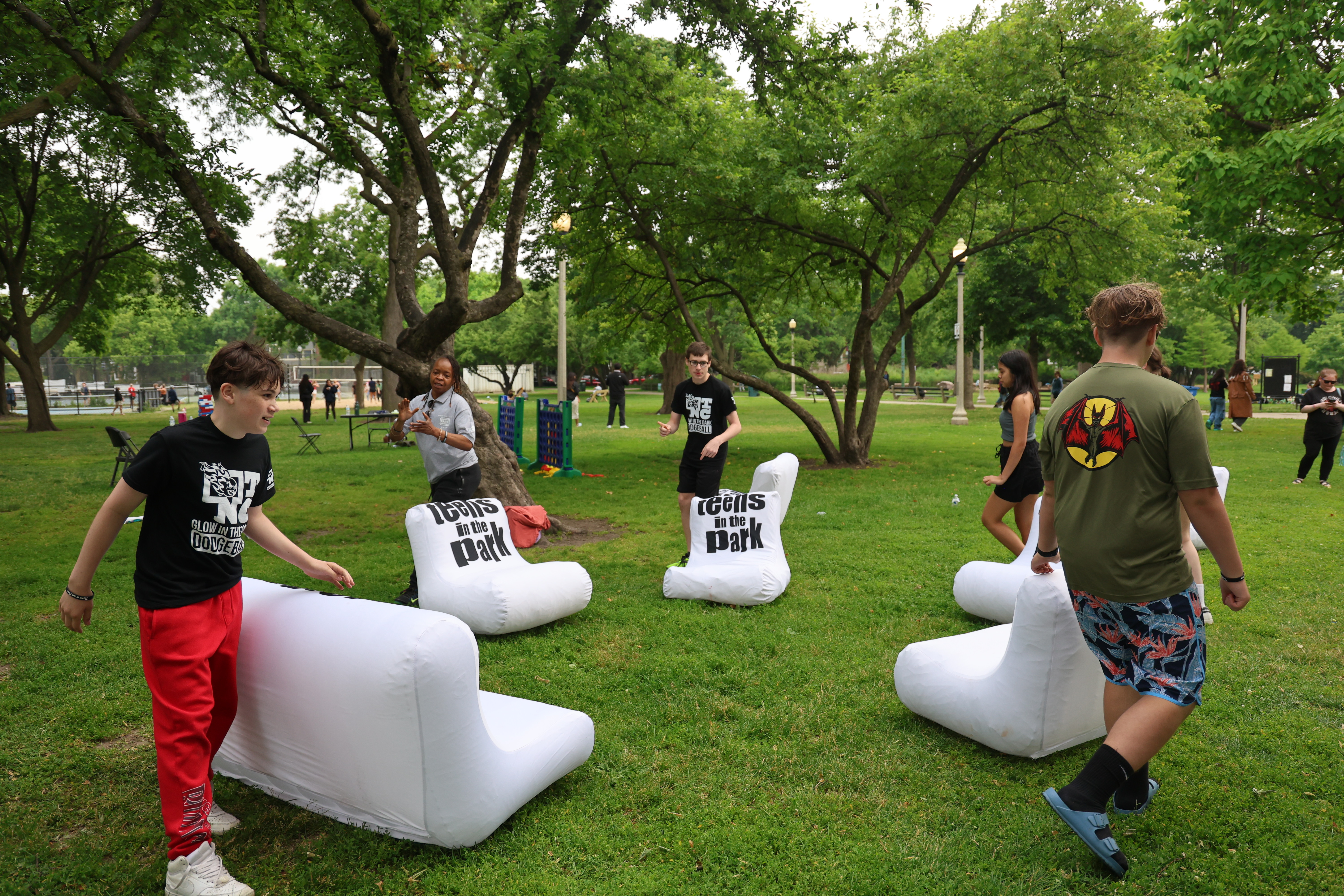 Teens gather in a park around inflatable chairs.